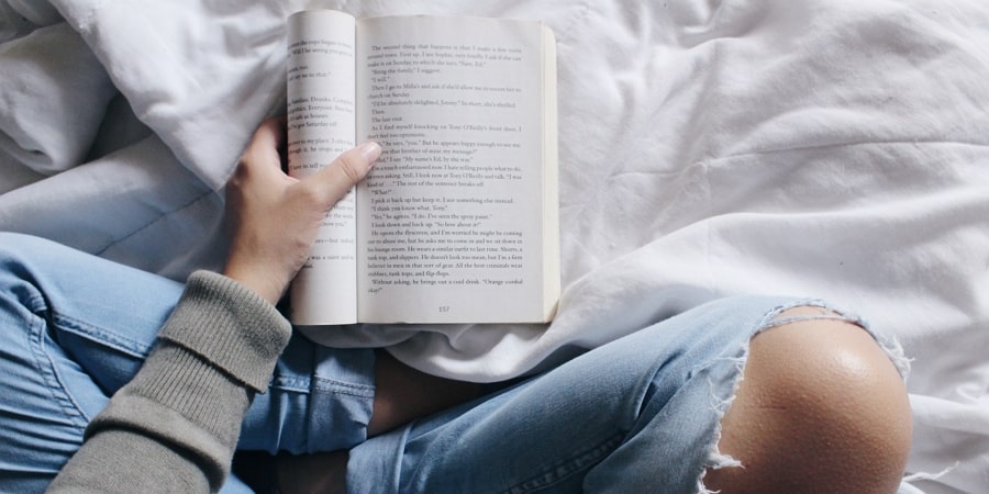A woman reading a book on her bed